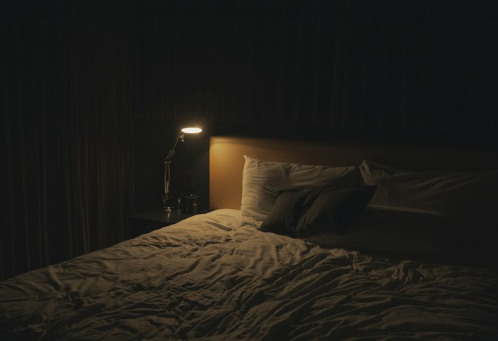 Ein schwach beleuchtetes Schlafzimmer mit Nachttischlampe