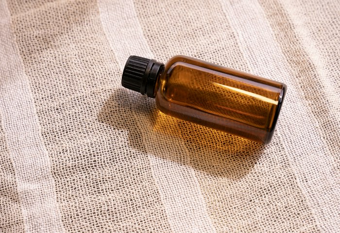Eine kleine braune Glasflasche auf hellem Stoff