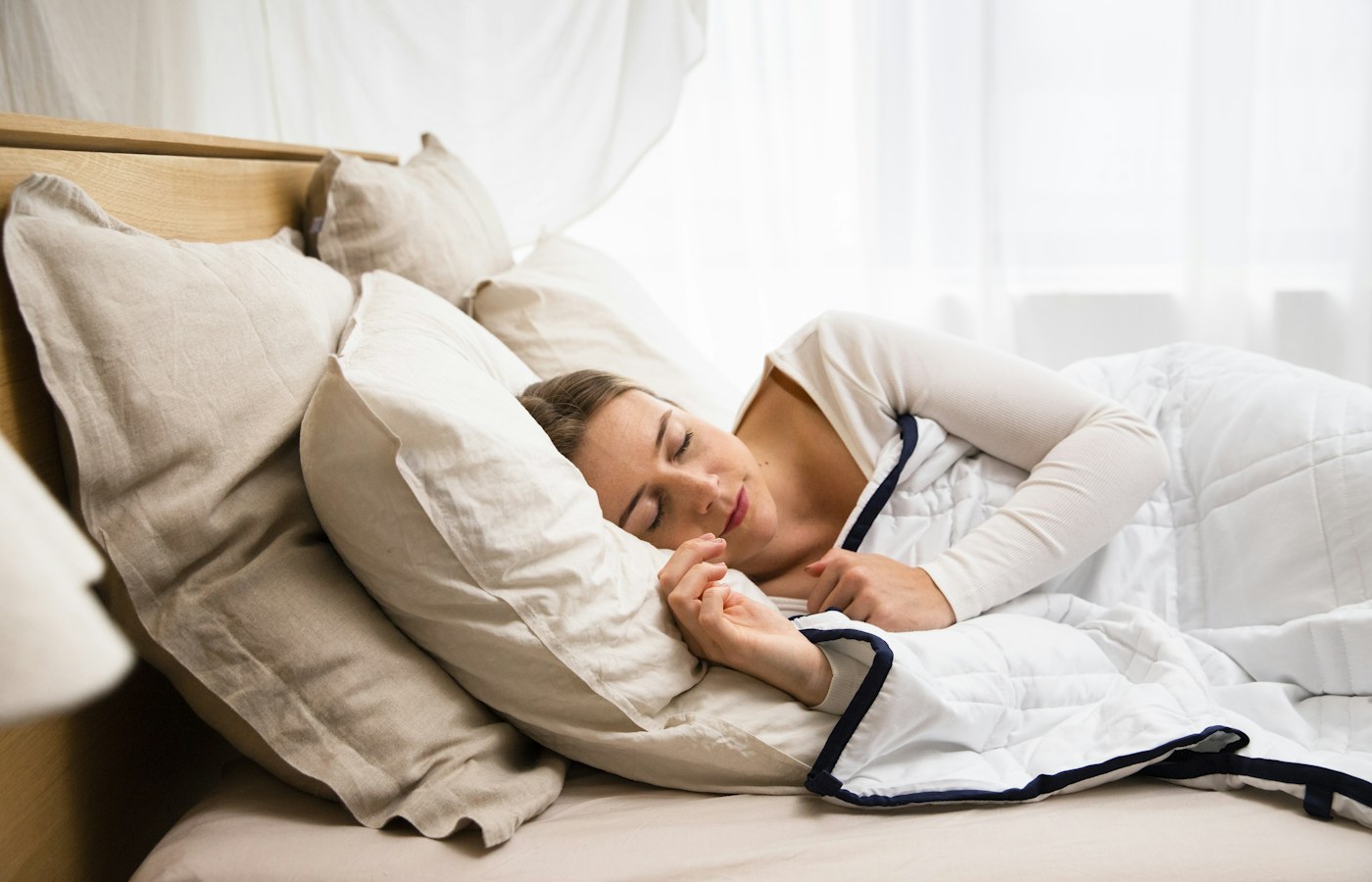 Eine Frau schläft in einem hellen Bett